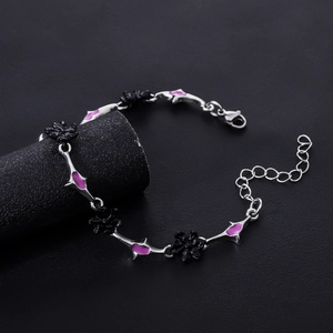 Gothic silver bracelet with black flowers and purple enamel on a dark pedestal