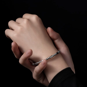 Gros plan du bracelet à perles en acier inoxydable argenté sur fond noir minimaliste