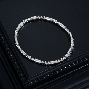 Gros plan d'un bracelet en acier inoxydable argenté avec perles polies et maillons cylindriques