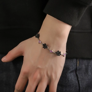 Close-up of a punk style silver chain bracelet featuring black flowers and purple accents