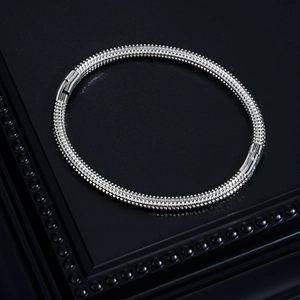 Macro detail of silver stainless steel choker with conical studs on black leather background