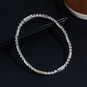 Gros plan d'un bracelet en acier poli avec boules et barres sur fond en cuir noir