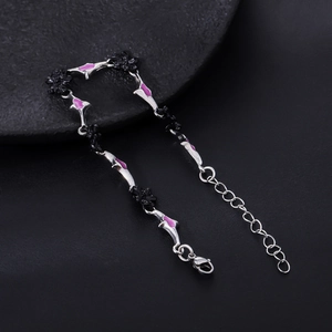 Close-up of black floral links and purple enamel charms on a silver metal chain bracelet