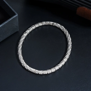 Macro shot of silver stainless steel bracelet with woven diamond texture on black leather
