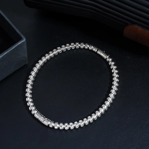 Detailed shot of silver textured bead bracelet with cylinder clasp on black surface