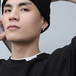 Gros plan d'une boucle d'oreille anneau argentée minimaliste portée par un mannequin homme