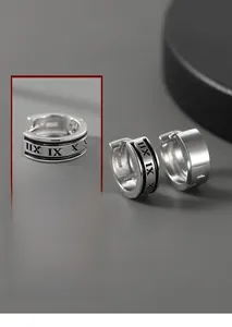 Détail de boucles d'oreilles cylindriques argentées avec chiffres romains et émail noir