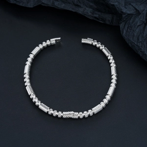 Détail d'un bracelet en acier inoxydable argenté avec texture torsadée et perles rondes