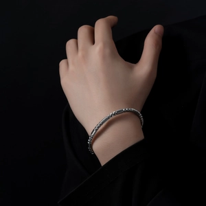 Détail d'un bracelet jonc torsadé en acier inoxydable argenté avec perles métalliques