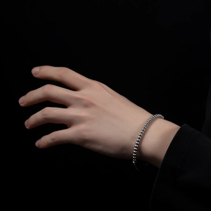 Close-up of high-polish silver stainless steel beaded bracelet on a model's wrist