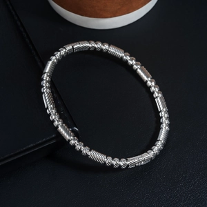 Vue détaillée du bracelet en acier argenté avec des perles torsadées et des cylindres