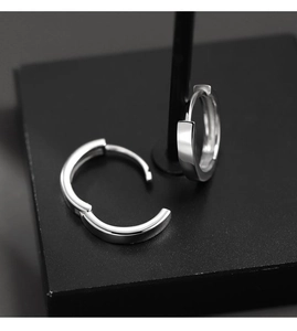 Gros plan de boucles d'oreilles créoles en argent sur un support noir au fini brillant