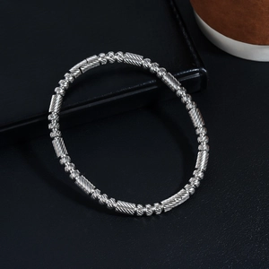 Détail d'un bracelet en acier inoxydable argenté avec perles texturées et gravure diagonale