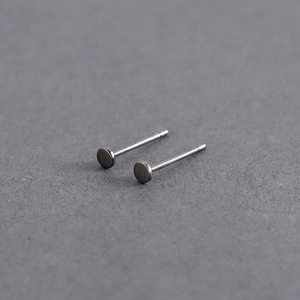 Close-up of minimalist silver geometric stud earrings with a matte brushed metal finish