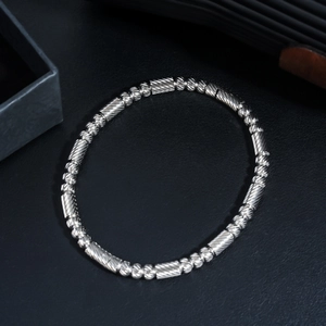 Détail du bracelet perlé en acier inoxydable argenté avec cylindres texturés sur cuir