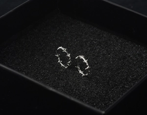 Gros plan de créoles épines argentées sur un présentoir de boîte à bijoux noire