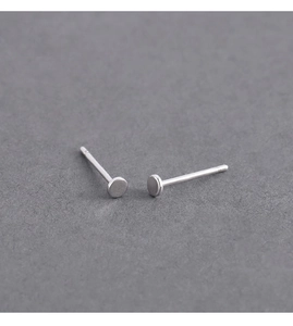 Macro detail of minimalist round flat-head stud earrings with polished silver metal finish