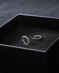 Détail macro de boucles d'oreilles anneaux épines argentées sur velours noir gothique