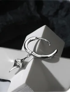 Dettaglio macro di orecchino a cerchio in argento con ciondolo a stella e zircone lucido