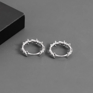 Boucles d'oreilles créoles épines en argent style punk sur fond gris foncé moderne