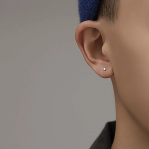 Minimalist silver gear shaped stud earrings with white enamel inlay shown on ear