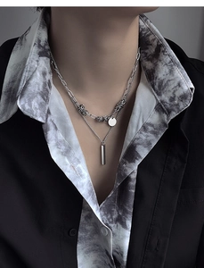 Détail d'un collier double en argent avec pendentif barre verticale et pièce ronde