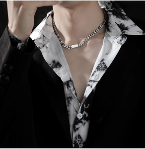 Macro detail of silver Cuban chain necklace with a rectangular metal plate for men