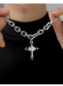 Dettaglio del ciondolo a croce d'argento con cristalli e smalto nero su catena spessa