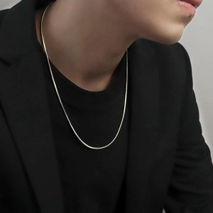 Minimalist silver snake bone chain necklace in titanium steel worn by male model