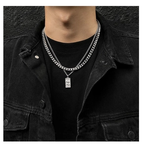 Close-up of double-layered silver chain necklace with Venus tag pendant on black denim