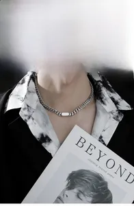 Detail view of a thick silver Cuban link chain with a smooth rectangular plaque on a male model