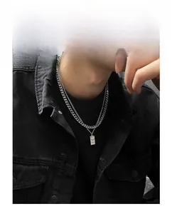 Close-up of double-layer silver Cuban link necklace with rectangular pendant on a male model