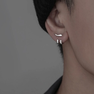 Ensemble minimaliste de clous et créoles en argent pour hommes, vue macro sur l'oreille