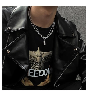 Detail of layered silver Cuban chain with a rectangular relief pendant on a male model