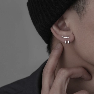 Détail d'un clou d'oreille en corne argentée avec strass et de petits anneaux minimalistes