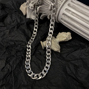 Polished silver cuban link chain necklace on black paper with classic marble decor