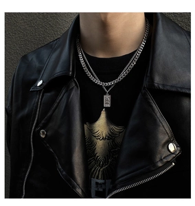 Detail of layered stainless steel necklace with portrait coin pendant on male model