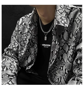 Detail of silver chain necklace with rectangular Venus relief pendant on snakeskin shirt