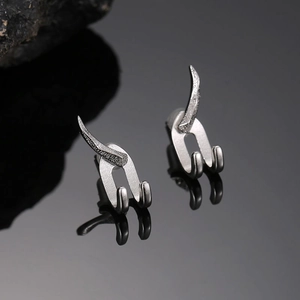 Détail de boucles d'oreilles punk argentées avec crochets pointus et doubles fourches