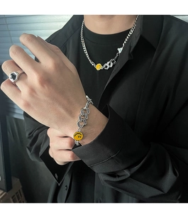 Dettaglio di collana e bracciale a catena groumette d'argento con ciondoli smiley gialli