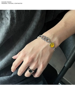 Dettaglio del bracciale a catena argento con ciondolo smiley giallo e maglie in zircone