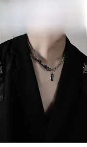 Gros plan du pendentif rectangle noir avec chaîne asymétrique argentée sur modèle