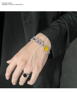 Dettaglio del bracciale a catena argentata con un vivace ciondolo giallo a forma di sorriso