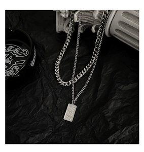 Detail of silver double-layered Cuban chain necklace with a vintage engraved rectangular pendant