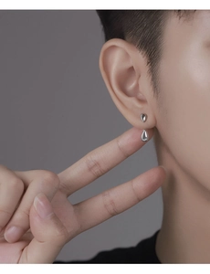 Gros plan d'une boucle d'oreille goutte d'eau en argent au design poli à double goutte