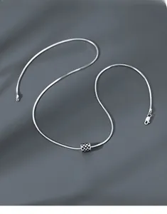 Detailed close-up of a silver checkerboard waist pendant on a snake bone chain necklace