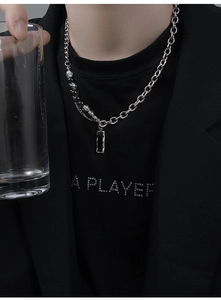Détail d'un collier pour homme avec perles asymétriques et pendentif rectangulaire noir