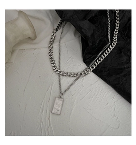 Detail of silver double-layered necklace featuring a Venus pendant and chunky Cuban chain