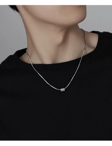 Detail of silver checkerboard square pendant on snake chain worn by a model