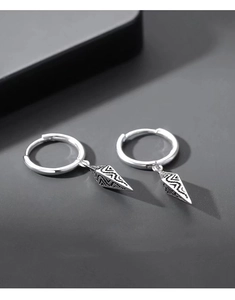 Detailed view of silver hoop earrings featuring textured conical pendants on grey background